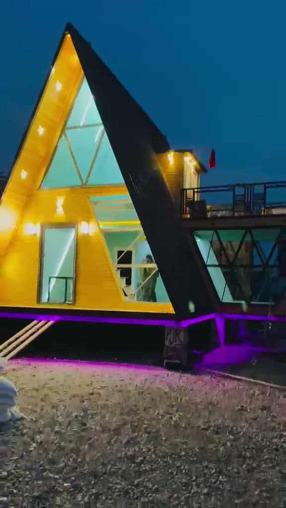 A-frame house at dusk showing the glazed gable, side wing and roof terrace